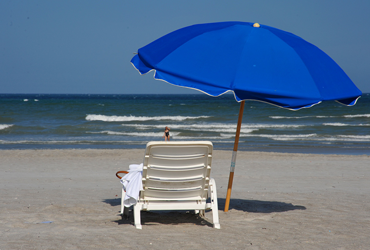 beach with blue umbrella and white chair